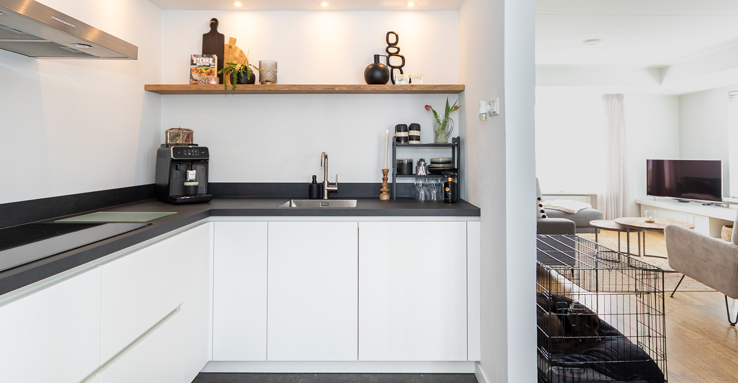 Moderne witte hoekkeuken met zwart werkblad 