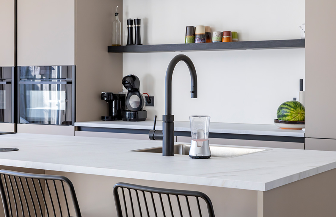 Moderne keuken met beige kasten, wit keukenblad, keukeneiland en zwarte kraan