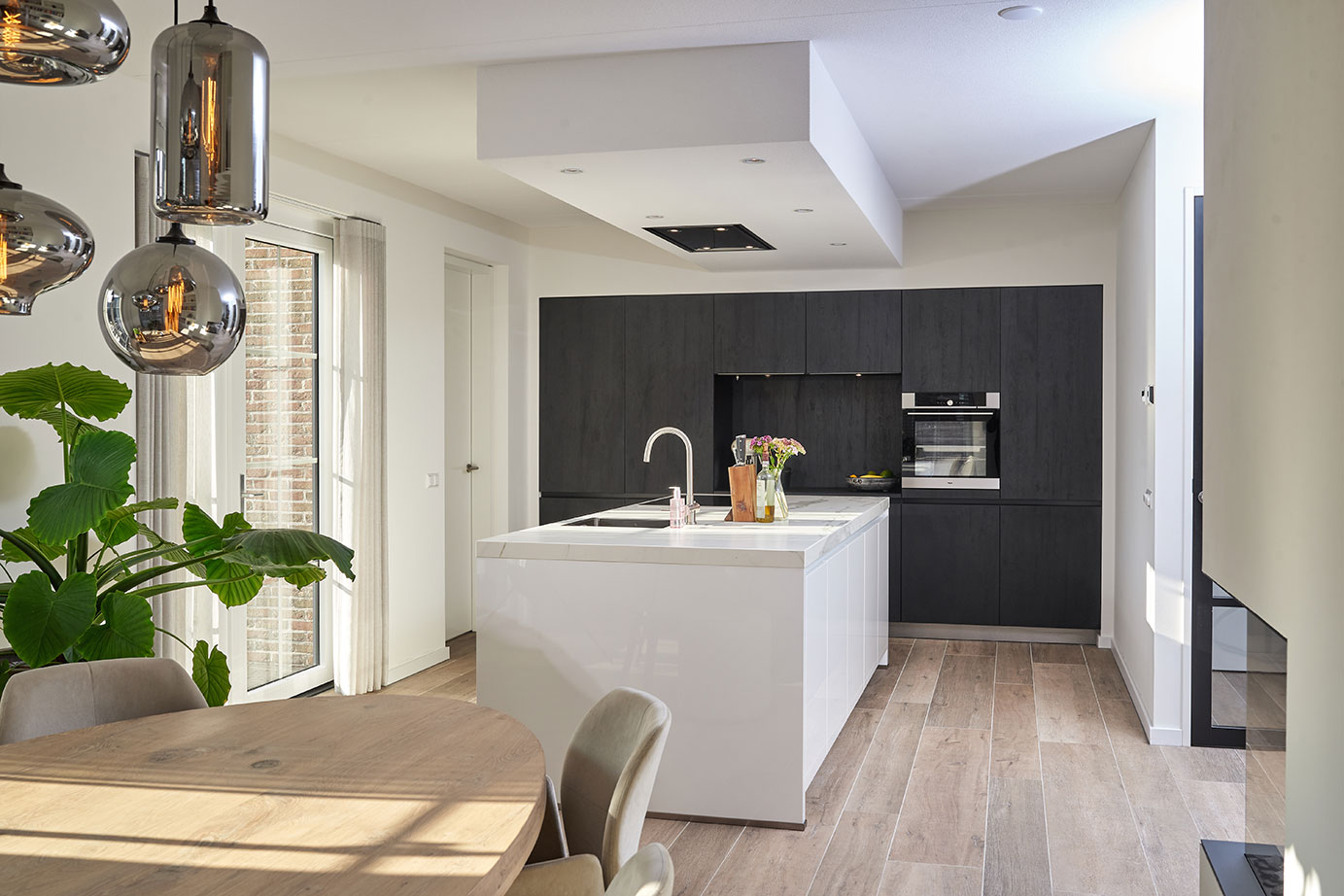 Witte eilandkeuken met zwarte kastenwand