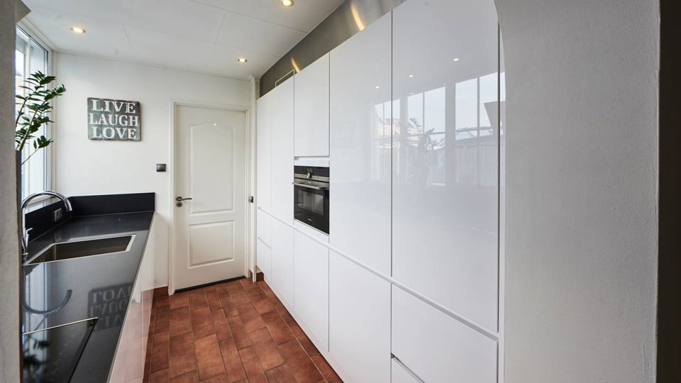 Parallelle hoogglans keuken wit met zwart aanrechtblad