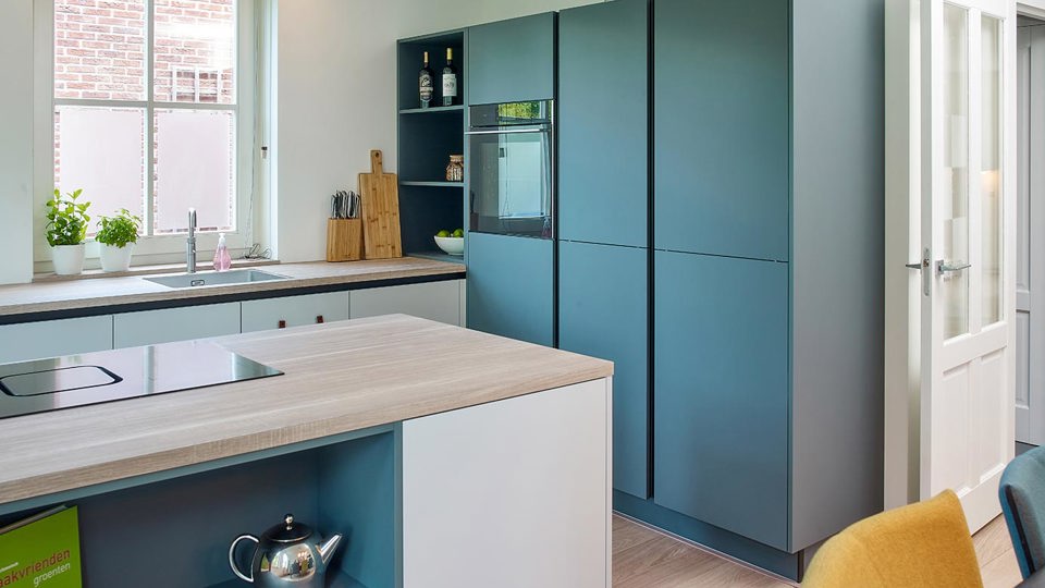 Groene keuken met eiland en kastenwand