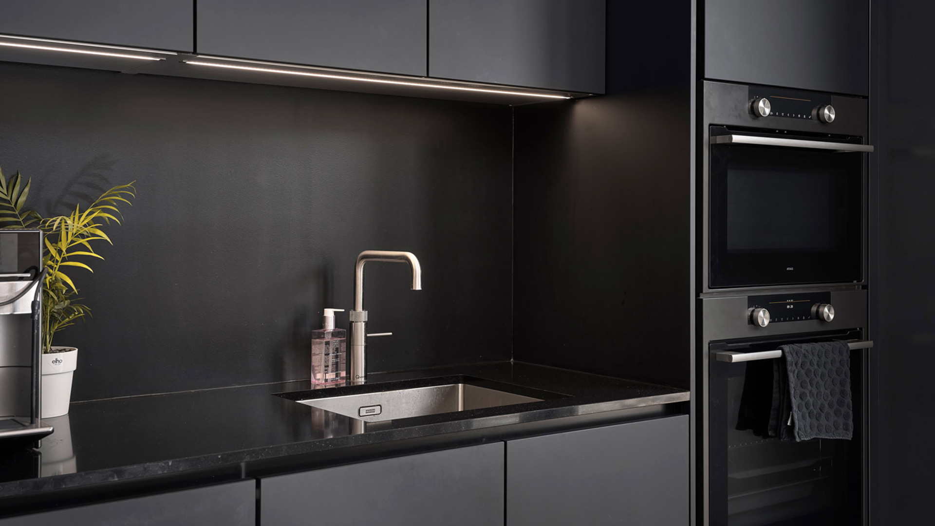 Rvs kraan en spoelbak in zwarte keuken Katwijk