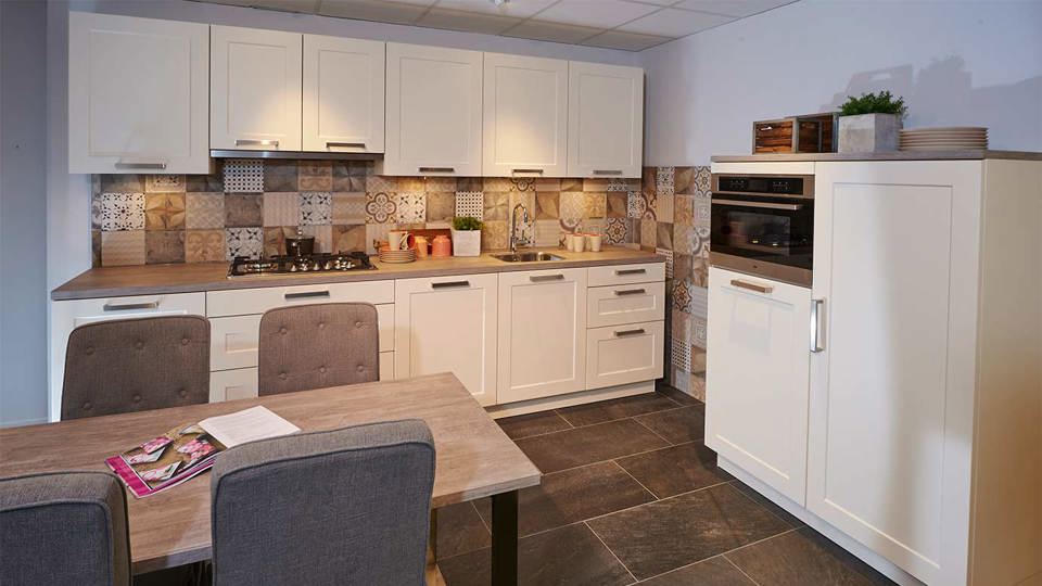 Een witte tijdloze keuken met kastenwand. Inclusief tabel en stoelen.