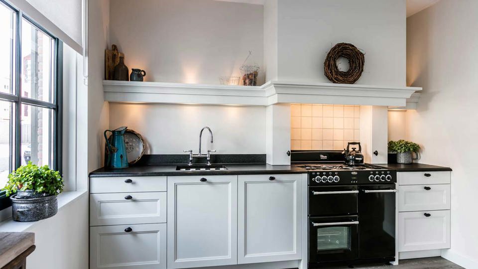 Landelijke rechte keuken met fornuis en schouw.