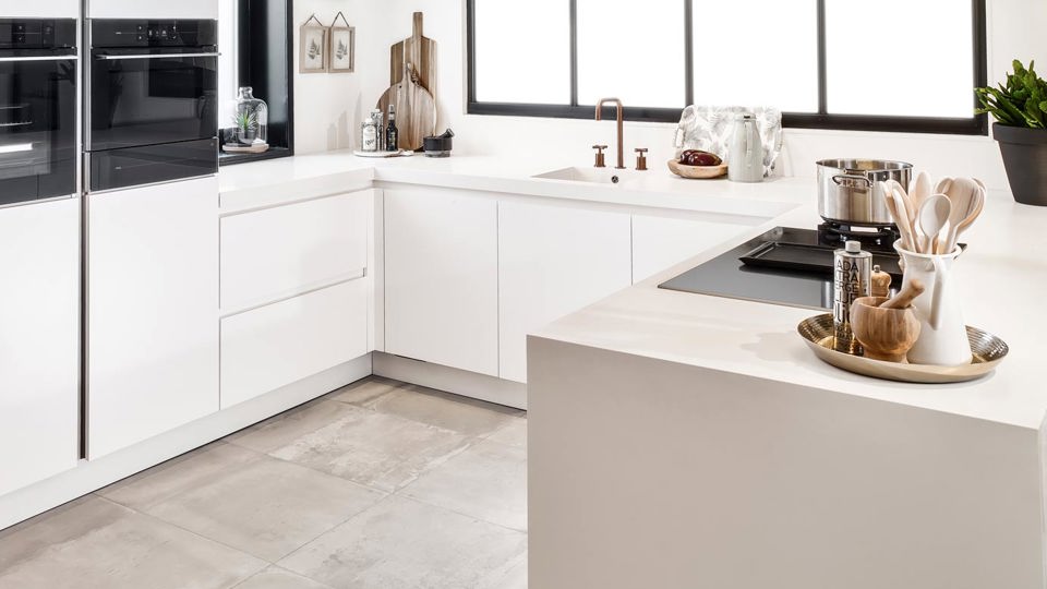 Een moderne u-keuken in de kleur mat wit, uitgevoerd in ton-sur-ton kleurstelling