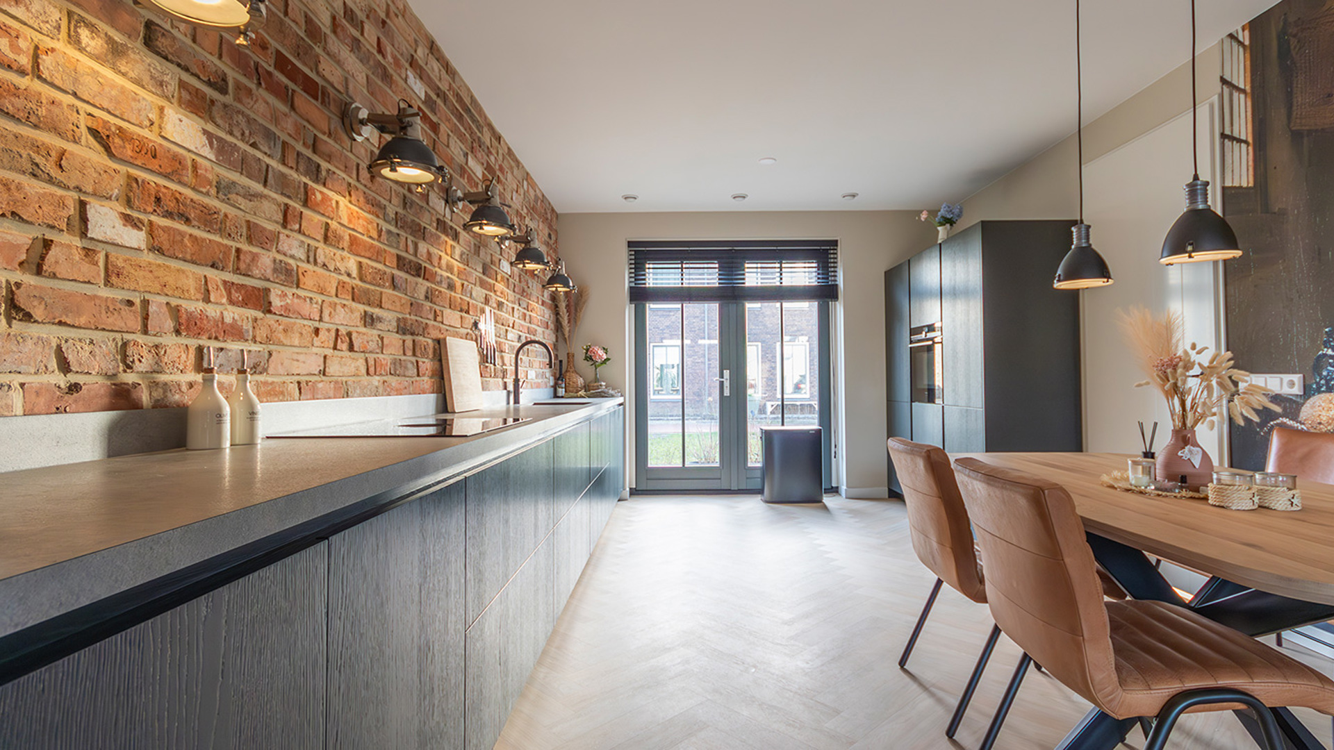 Compleet overzicht keuken, koelkast en eethoek met uitkijk op de tuin door groot raam